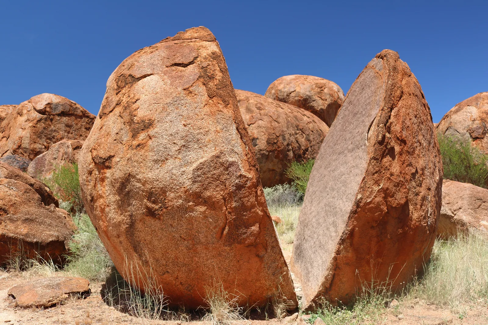Enormous rounded granite boulders glowing red against a deep blue sky at Karlu Karlu
