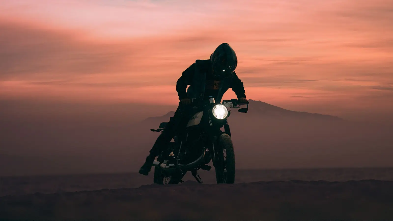 A motorcycle and rider against a sunset