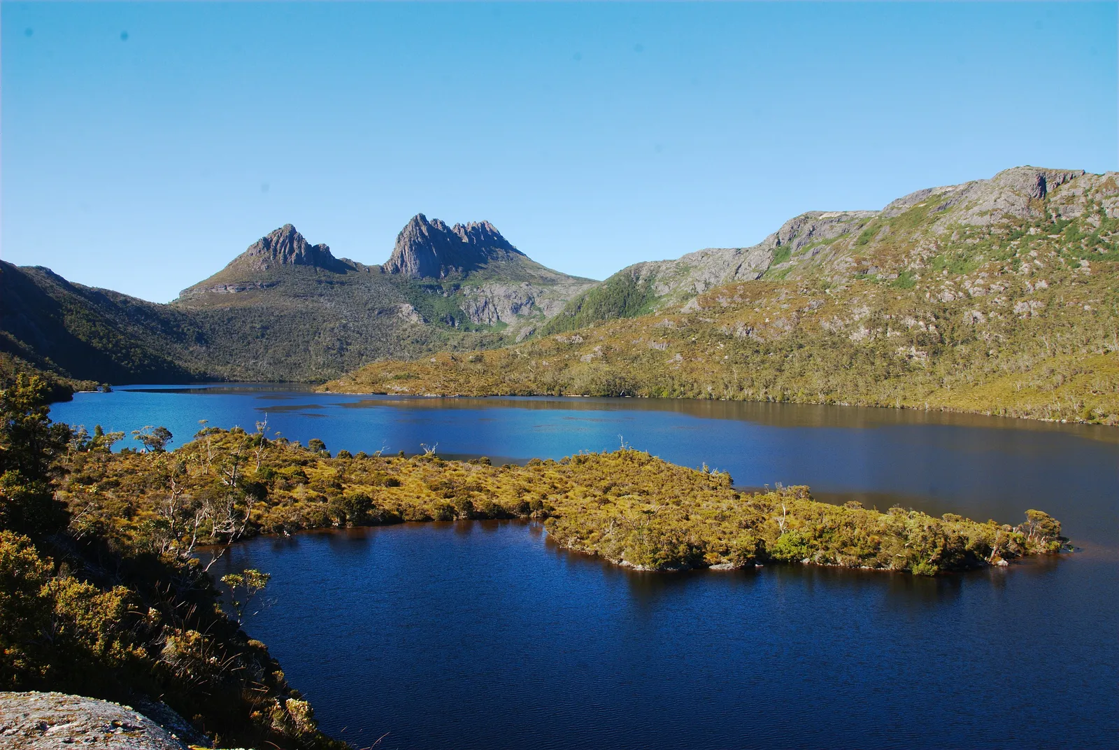Dove Lake in the foreground with the jagged dolerite peaks of Cradle Mountain rising behind under a clear sky
